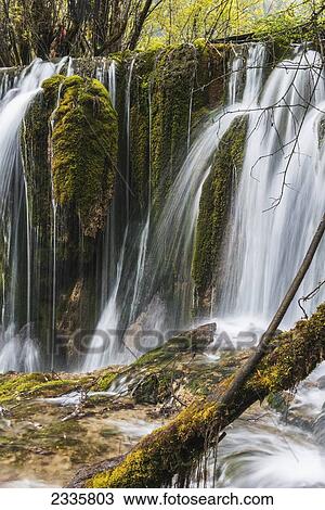 Stock Image - Waterfalls over cliffs covered in foliage. Fotosearch