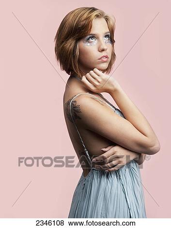 Young woman posed in the studio in a blue dress against a light pink backdrop; California, United States of America View Large Photo Image Stock Photo - Young woman posed in the studio in a blue dress against a light pink backdrop; California, United States of America. Fotosearch