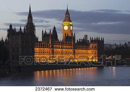 A Building And Clock Tower Along The Water's Edge Illuminated At Dusk; London, England View Large Photo Image Stock Photo - A Building And Clock Tower Along The Water's Edge Illuminated At Dusk; London, England. Fotosearch