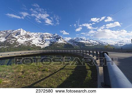 A Curve In The Road With The Swiss Alps In The Background; San Gottardo, Ticino, Switzerland View Large Photo Image Stock Image - A Curve In The Road With The Swiss Alps In The Background; San Gottardo, Ticino, Switzerland. Fotosearch
