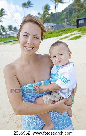 A Mother Holding Her Infant Son In Her Arms At Lanikai Beach; Kailua, Oahu, Hawaii, United States Of America View Large Photo Image Stock Image - A Mother Holding Her Infant Son In Her Arms At Lanikai Beach; Kailua, Oahu, Hawaii, United States Of America. Fotosearch
