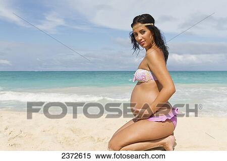 A pregnant woman poses on the beach at the water's edge; Honolulu, Hawaii, United States of America View Large Photo Image Stock Photography - A pregnant woman poses on the beach at the water's edge; Honolulu, Hawaii, United States of America. Fotosearch