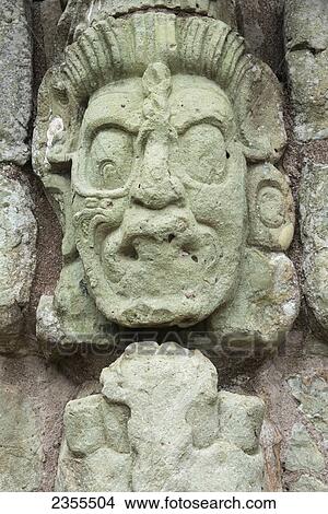 Picture - A Stone Face Carved Into A Stone Wall In A Maya Civilization At Copan Ruins; Copan, Honduras. Fotosearch