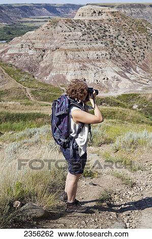 Stock Image - A Woman Photographs The Badlands; Drumheller, Alberta, Canada. Fotosearch