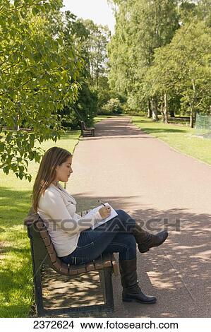 A woman sits on a park bench and writes in her journal; Honolulu, Hawaii, United States of America View Large Photo Image Picture - A woman sits on a park bench and writes in her journal; Honolulu, Hawaii, United States of America. Fotosearch