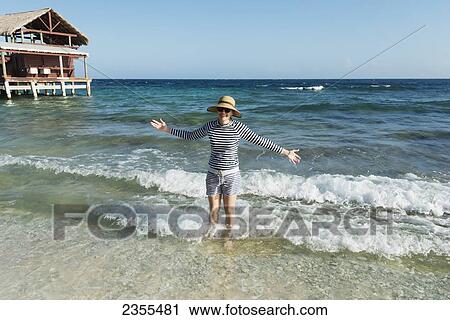 A Woman Stands In The Waves Beside A Hotel On The Coast; Utila, Bay Islands, Honduras View Large Photo Image Stock Image - A Woman Stands In The Waves Beside A Hotel On The Coast; Utila, Bay Islands, Honduras. Fotosearch