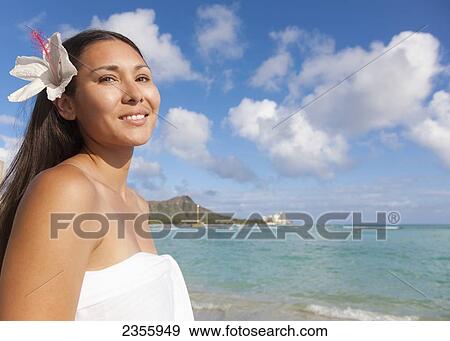 A Young Woman Poses On A Beach With A Hibiscus Flower In Her Hair; Waikiki, Oahu, Hawaii, United States Of America View Large Photo Image Stock Photo - A Young Woman Poses On A Beach With A Hibiscus Flower In Her Hair; Waikiki, Oahu, Hawaii, United States Of America. Fotosearch
