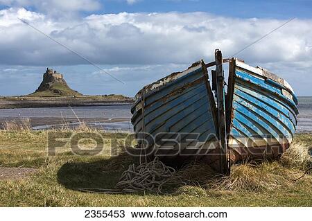 Stock Image - An Abandoned Boat On The Shore With Lindisfarne Castle In The Background; Lindisfarne, Northumberland, England. Fotosearch