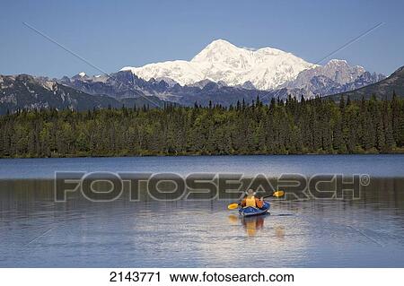 Stock Image - Man Paddling A Klepper Kayak On Byers Lake At Denali State Park. Mt. Mckinley Is Visible In The Background. August. Summer In The Interio Of Alaska.. Fotosearch