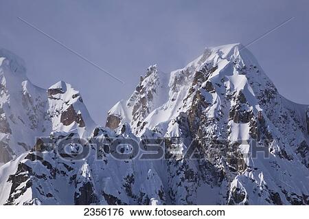Stock Photograph - Misty Clouds Swirl Across The Summit Of Roostercomb, A Peak In The Alaska Range Near Mt. Mckinley, Taken From Ruth Glacier, Ruth Amphitheater In Winter, Denali National Park And Preserve; Alaska, United States Of America. Fotosearch
