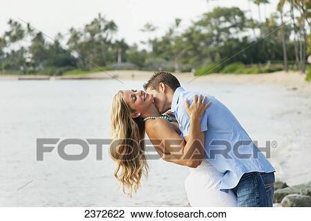 Portrait of a couple kissing on a beach at the water's edge; Honolulu, Hawaii, United States of America View Large Photo Image Stock Image - Portrait of a couple kissing on a beach at the water's edge; Honolulu, Hawaii, United States of America. Fotosearch