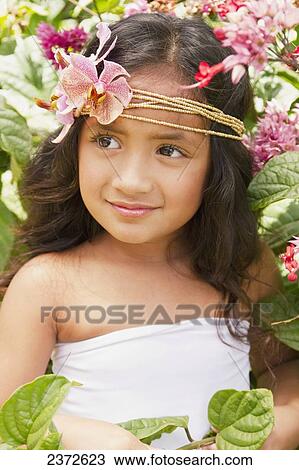 Stock Image - Portrait of a young girl with tropical flowers in her hair; Honolulu, Hawaii, United States of America. Fotosearch