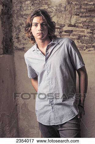 Stock Photo - Portrait Of A Young Man Standing Against A Stone And Concrete Wall; Tarifa, Cadiz, Andalusia, Spain. Fotosearch