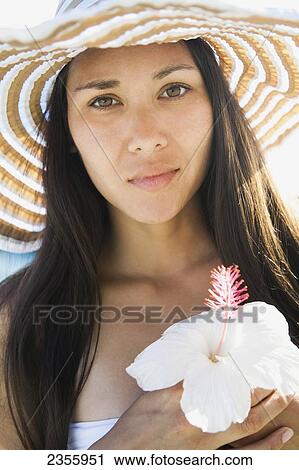 Portrait Of A Young Woman In A Sunhat Holding An Hibiscus Flower; Waikiki, Oahu, Hawaii, United States Of America View Large Photo Image Stock Image - Portrait Of A Young Woman In A Sunhat Holding An Hibiscus Flower; Waikiki, Oahu, Hawaii, United States Of America. Fotosearch