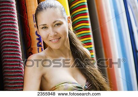 Stock Photo - Portrait Of A Young Woman Standing Against Colourful Surfboards; Waikiki, Oahu, Hawaii, United States Of America. Fotosearch