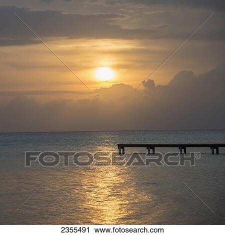 Silhouette Of A Dock Leading Out To Water With The Sun Setting In A Dramatic Sky; Utila, Bay Islands, Honduras View Large Photo Image Stock Image - Silhouette Of A Dock Leading Out To Water With The Sun Setting In A Dramatic Sky; Utila, Bay Islands, Honduras. Fotosearch