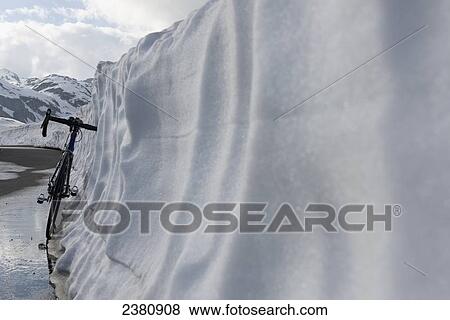 A bicycle parked on a path leaning against a wall of snow; San Gottardo, Uri, Switzerland View Large Photo Image Stock Photo - A bicycle parked on a path leaning against a wall of snow; San Gottardo, Uri, Switzerland. Fotosearch
