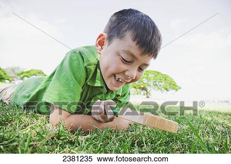 A boy looking through a magnifying glass at the grass; Honolulu, Oahu, Hawaii, United States of America View Large Photo Image Stock Photography - A boy looking through a magnifying glass at the grass; Honolulu, Oahu, Hawaii, United States of America. Fotosearch