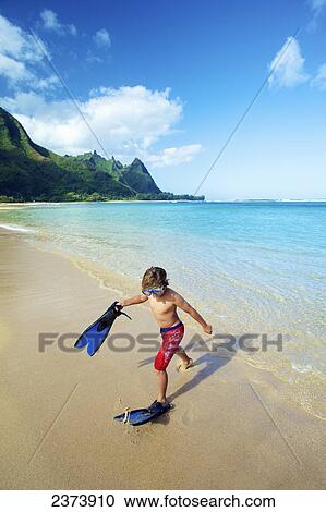 Stock Image - A boy on the beach with snorkelling gear; Kauai, Hawaii, United States of America. Fotosearch