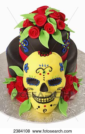 Stock Photo - A cake decorated with a skeleton mask and red rosettes for the Mexican day of the dead holiday; Alberta, Canada. Fotosearch