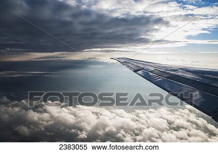 Stock Photography - A commercial jet flies through the clouds; Colorado, United States of America. Fotosearch