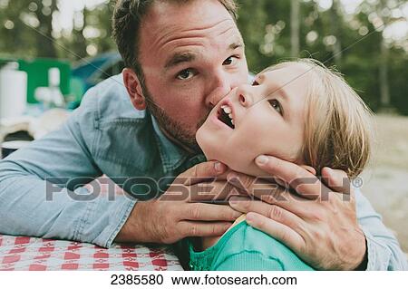 Stock Image - A father kissing his daughter on the cheek; Peachland, British Columbia, Canada. Fotosearch