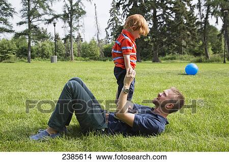 A father plays with his young son on a grass field; Stony Plain, Alberta, Canada View Large Photo Image Picture - A father plays with his young son on a grass field; Stony Plain, Alberta, Canada. Fotosearch