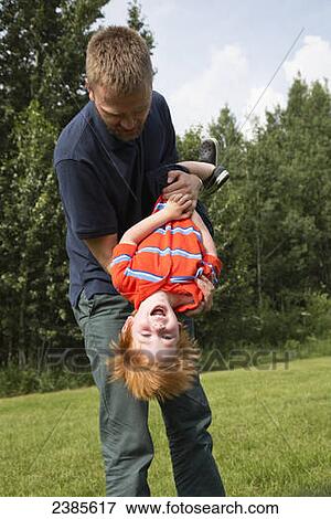 A father plays with his young son on a grass field; Stony Plain, Alberta, Canada View Large Photo Image Stock Photo - A father plays with his young son on a grass field; Stony Plain, Alberta, Canada. Fotosearch