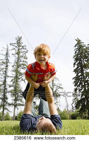 A father plays with his young son on a grass field; Stony Plain, Alberta, Canada View Large Photo Image Stock Photograph - A father plays with his young son on a grass field; Stony Plain, Alberta, Canada. Fotosearch
