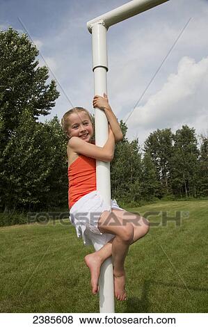 Stock Photo - A girl climbing the soccer goalpost in a park; Stony Plain, Alberta, Canada. Fotosearch