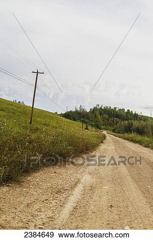 Stock Photo - A gravel road leading travellers away from the highway down to the forest; Fort McMurray, Alberta, Canada. Fotosearch