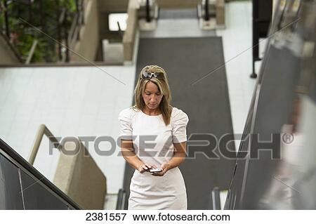 Stock Photo - A mature professional businesswoman in a downtown office environment using cell phone; Edmonton, Alberta, Canada. Fotosearch