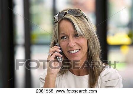 A mature professional businesswoman in a downtown office environment using cell phone; Edmonton, Alberta, Canada View Large Photo Image Stock Photo - A mature professional businesswoman in a downtown office environment using cell phone; Edmonton, Alberta, Canada. Fotosearch
