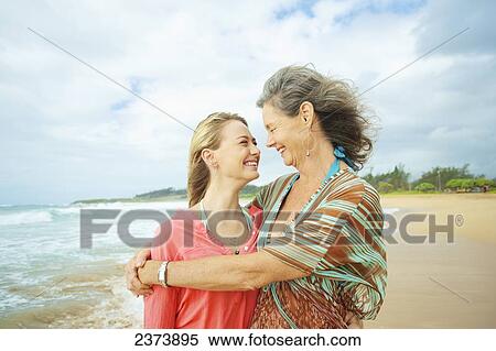 Stock Photography - A mother and daughter together on the beach at the water's edge; Kauai, Hawaii, United States of America. Fotosearch