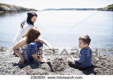 Stock Photography - A mother playing with her children at the water's edge; Victoria, British Columbia, Canada. Fotosearch