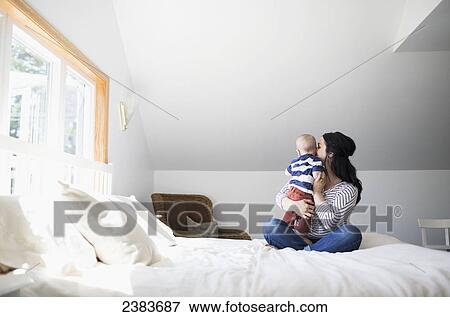 A mother plays with her infant son on a bed; Victoria, British Columbia, Canada View Large Photo Image Stock Photo - A mother plays with her infant son on a bed; Victoria, British Columbia, Canada. Fotosearch