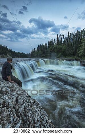 A person watches as the Trout River flows over Sambaa Deh Falls in Sambaa Deh Territorial Park; Northwest Territories, Canada View Large Photo Image Stock Image - A person watches as the Trout River flows over Sambaa Deh Falls in Sambaa Deh Territorial Park; Northwest Territories, Canada. Fotosearch
