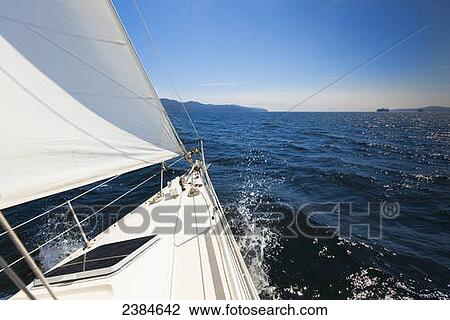 Stock Image - A sailboat sails in the Gulf Islands on a sunny day; British Columbia, Canada. Fotosearch