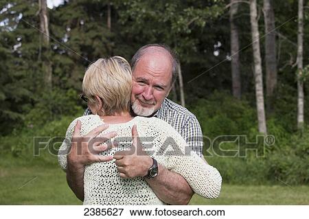 Stock Photo - A senior couple in an embrace and the husband giving the thumbs up sign; Stony Plain, Alberta, Canada. Fotosearch