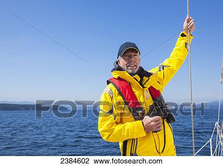 A senior man with binoculars looks over the Gulf Islands while sailing near Vancouver Island; British Columbia, Canada View Large Photo Image Stock Image - A senior man with binoculars looks over the Gulf Islands while sailing near Vancouver Island; British Columbia, Canada. Fotosearch