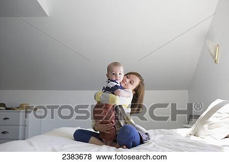 A sister holding her baby brother on a bed at home; Victoria, British Columbia, Canada View Large Photo Image Stock Photo - A sister holding her baby brother on a bed at home; Victoria, British Columbia, Canada. Fotosearch