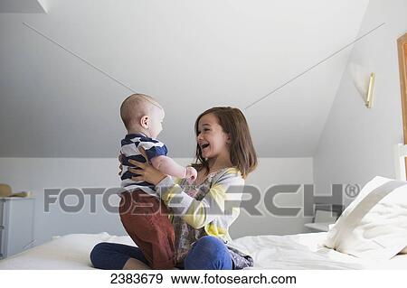 A sister playing with her baby brother on a bed at home; Victoria, British Columbia, Canada View Large Photo Image Stock Photo - A sister playing with her baby brother on a bed at home; Victoria, British Columbia, Canada. Fotosearch