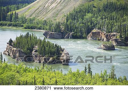 A small island covered with trees in a river with a steep slope of a mountain along the shoreline; Yukon, Canada View Large Photo Image Stock Image - A small island covered with trees in a river with a steep slope of a mountain along the shoreline; Yukon, Canada. Fotosearch