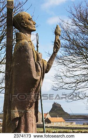 A statue of an historic figure standing against a cross and a view of Lindisfarne Castle in the distance; Holy Island, Northumberland, England View Large Photo Image Stock Image - A statue of an historic figure standing against a cross and a view of Lindisfarne Castle in the distance; Holy Island, Northumberland, England. Fotosearch