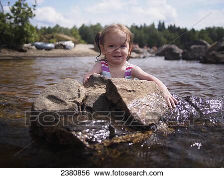 A toddler holds on to a rock while wading in Flagstaff Lake; Maine, United States of America View Large Photo Image Stock Photograph - A toddler holds on to a rock while wading in Flagstaff Lake; Maine, United States of America. Fotosearch