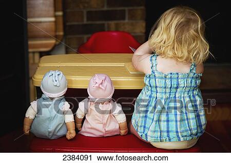 A toddler sits at a play table with her two dolls; Alberta, Canada View Large Photo Image Stock Image - A toddler sits at a play table with her two dolls; Alberta, Canada. Fotosearch