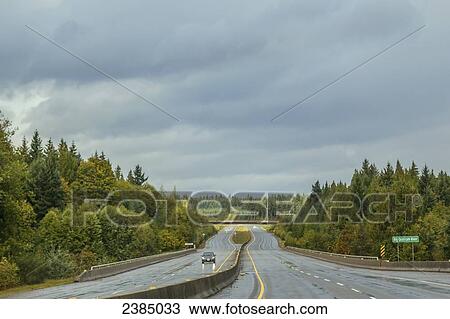 Stock Image - A wet road under storm clouds; Qualicum, British Columbia, Canada. Fotosearch