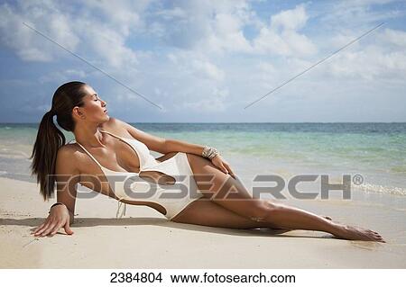 Picture - A woman in a sexy white bathing suit posing on a beach; Oahu, Hawaii, United States of America. Fotosearch