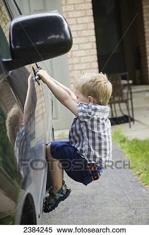Stock Photography - A young boy playing on a car; Guelph, Ontario, Canada. Fotosearch