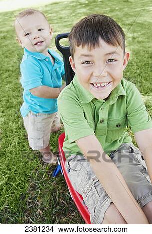 A young boy pulling a wagon in the park with his big brother in it; Honolulu, Oahu, Hawaii, United States of America View Large Photo Image Picture - A young boy pulling a wagon in the park with his big brother in it; Honolulu, Oahu, Hawaii, United States of America. Fotosearch